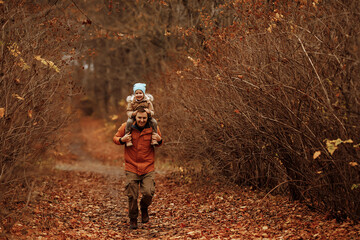 Happy family father and daughter on a walk in the autumn leaf fall in the park. Concept of...