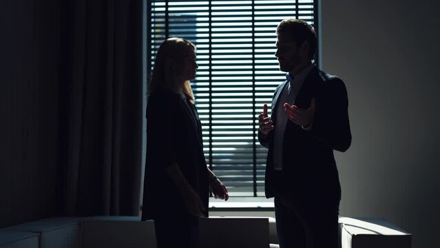Side view of two business people standing in executive's office and talking about common collaboration. Male and female adults wearing formal clothes agreeing financial questions of new startup.