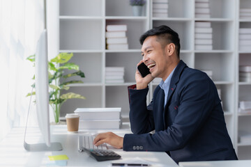 Committed Young Asian Businessman Professional work Talking on Phone in the office.