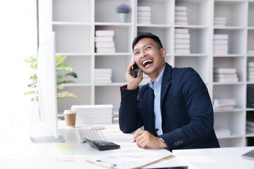 Committed Young Asian Businessman Professional work Talking on Phone in the office. © amnaj