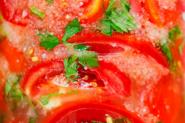 Tomatoes red cut, pickled with herbs and garlic in glass jar close-up, selective focus, background, vertical frame