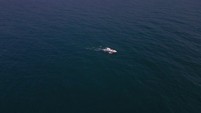 Aerial view of a pleasure boat racing through the sea waves, creating a mesmerizing picture of speed and freedom.