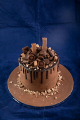 Chocolate Overloaded Cake with rose flowers, knife and fork served on board isolated on napkin side view of cafe baked food
