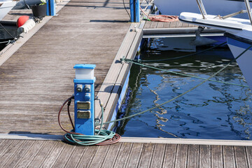 Stationary station for supplying moored yachts and boats with electricity and water at the dock