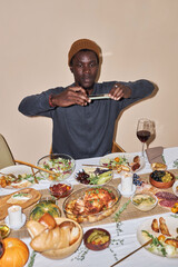 Vertical portrait of young Black man taking photo of Thanksgiving dinner table shot with flash