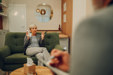 A senior female patient is having a session with a psychotherapist in a doctor's office.