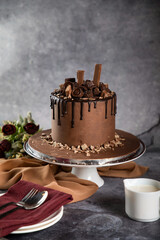 Chocolate Overloaded Cake with rose flowers, knife and fork served on board isolated on napkin side view of cafe baked food