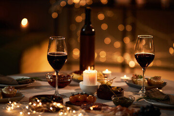 Background image of two wine glasses on dinner table with Christmas lights and candles, copy space