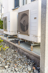 Two air source heat pumps installed outside of modern family house, green renewable energy concept...