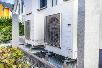 Two air source heat pumps installed outside of modern family house, green renewable energy concept...