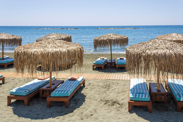 Sun beds and palm umbrellas on sandy sea beach, Limassol, Cyprus