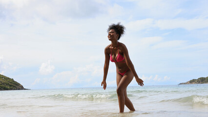 Fototapeta na wymiar Joyful black girl play water on sea at tropical beach, Summer vacation