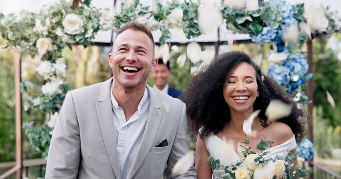 Couple, wedding and walk with flower confetti for event, celebration and outdoor in nature. Girl, happy interracial marriage and floral bouquet in park, holding hands or fist in air, pride or party - Powered by Adobe