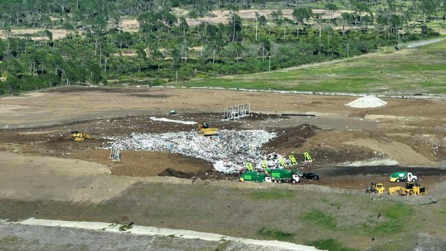 Waste managment concept. Large landfill site with bulldozers burying trash under ground. Harmful impact of modern consumerism on environment