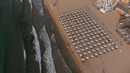 aerial view of beach with umbrellas down, sand and sea waves landscape.