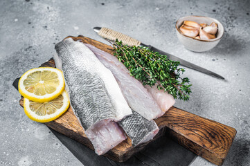 Fresh Raw Sea Bass fillets, Branzino fish with thyme and lemon. Gray background. Top view