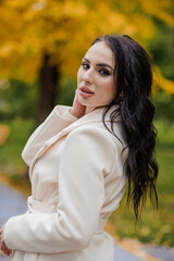 Girl in a white coat in an autumn park