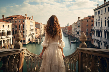 Fototapeta na wymiar Woman traveler standing on a picturesque bridge in Venice, Italy, overlooking the Grand Canal and historic buildings