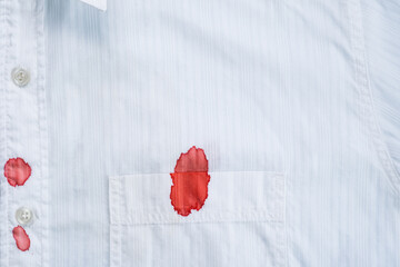 A drops of blood a white shirt. Stained clothing. daily life stain concept. - obrazy, fototapety, plakaty