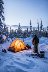 Winter camper setting up a tent in a snowy wilderness