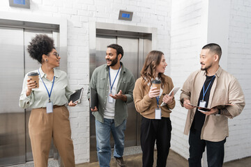 cultural diversity, happy multicultural creative team with badges chatting near office elevators