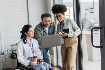 group happy diverse business people, disabled woman on wheelchair looking at laptop with coworkers