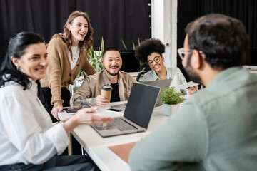 happy interracial business team looking at colleague on blurred foreground, brainstorming