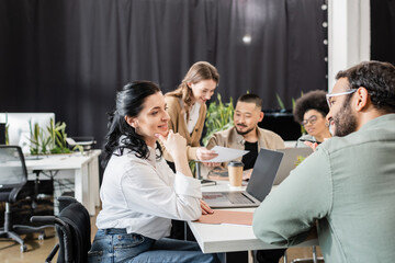 cheerful team lead listening ideas of indian coworker near multicultural business people in office