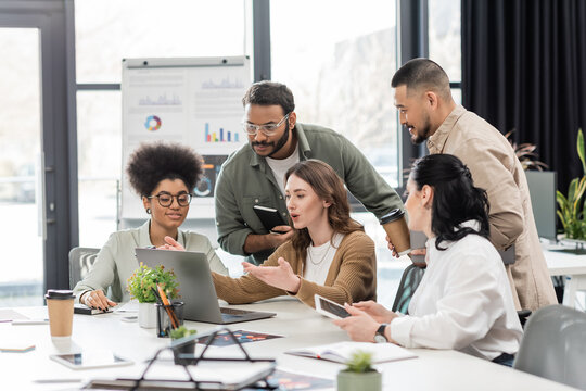 candid photo, interracial business team discussing project and sharing ideas in modern coworking