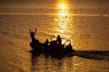 Hommes polynésiens dans un zodiaque à Tahiti au coucher du soleil
