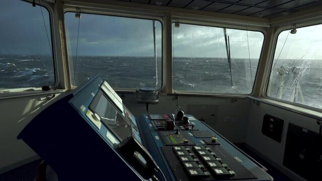 Vessel in storm. Window wipers are working. Strong pitching. Sun in storm. White foam on sea. View from navigating bridge