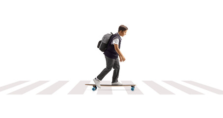 Full length profile shot of a schoolboy in a uniform riding a skateboard at a pedestrian crossing