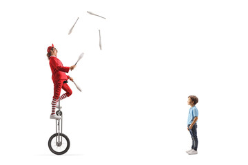 Little boy watching an acrobat riding a giraffe unicycle and juggling - obrazy, fototapety, plakaty