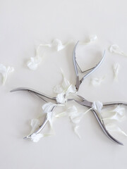 Manicure tools in white flower petals on white background, top view, there is space for text. Beauty salon, aesthetics. High quality photo