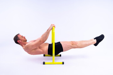 Front and side view photo of an strong young man exercising on parallel bars in studio.