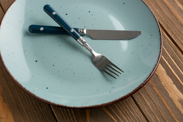 Silver fork with knife and plate on wooden table