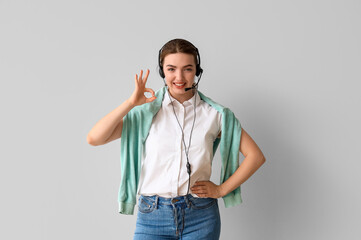 Fototapeta premium Female technical support agent showing OK on light background