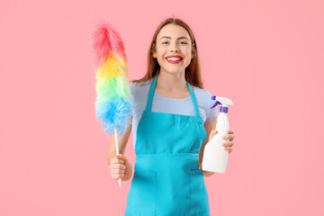 Young woman with bottle of detergent and pp-duster on pink background