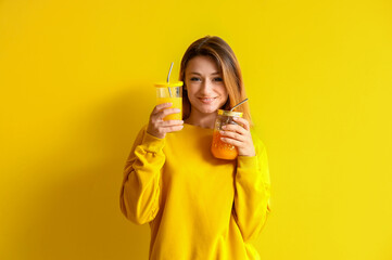 Young woman with glasses of juice on yellow background