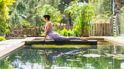Woman practicing yoga, lying in Cobra pose (Bhujangasana exercise) outdoors