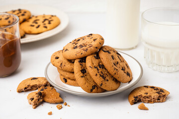 Plate of tasty cookies with chocolate chips on white background