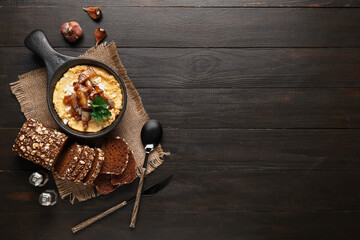 Frying pan of tasty banosh with bread on black wooden background