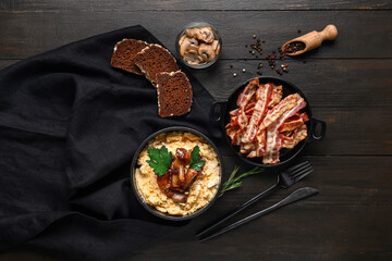 Bowl of tasty banosh, bread, mushrooms and bacon on black wooden background