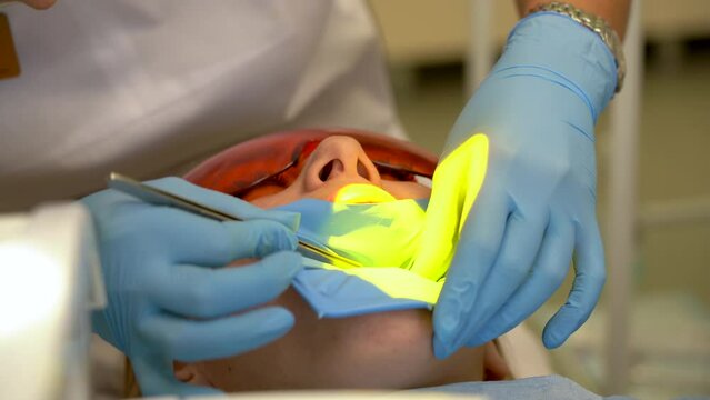 Doctor working with instruments in patient's open mouth for dental treatment