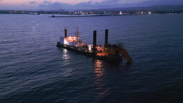 Aerial view of a dredge vessel with a dredging bucket, actively deepening the navigational fairway at sea, ensuring safe navigation.