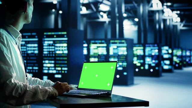 Asian technician using mockup laptop to implement artificial intelligence parallel processing. Specialist works on chroma key device enabling AI systems to do machine learning inference