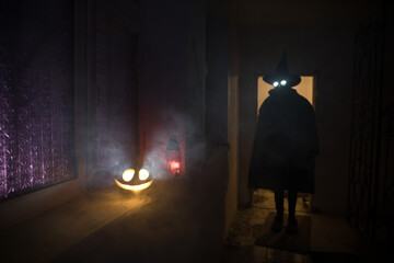 Obraz na płótnie Canvas Halloween concept. Creepy silhouette in the dark corridor with pumpkin head. Toned light with fog on background.