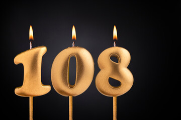 Golden candle 108 with flame - Birthday card on dark luxury background