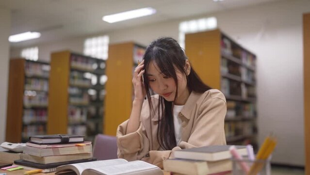 Depressed young woman student. sad teenager studying preparing for exam test in the university library.