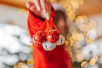 Bells for the Christmas tree.child holding decorative bells in his hand on a shining Christmas tree background. Christmas tree decoration with bells.Christmas decorations.